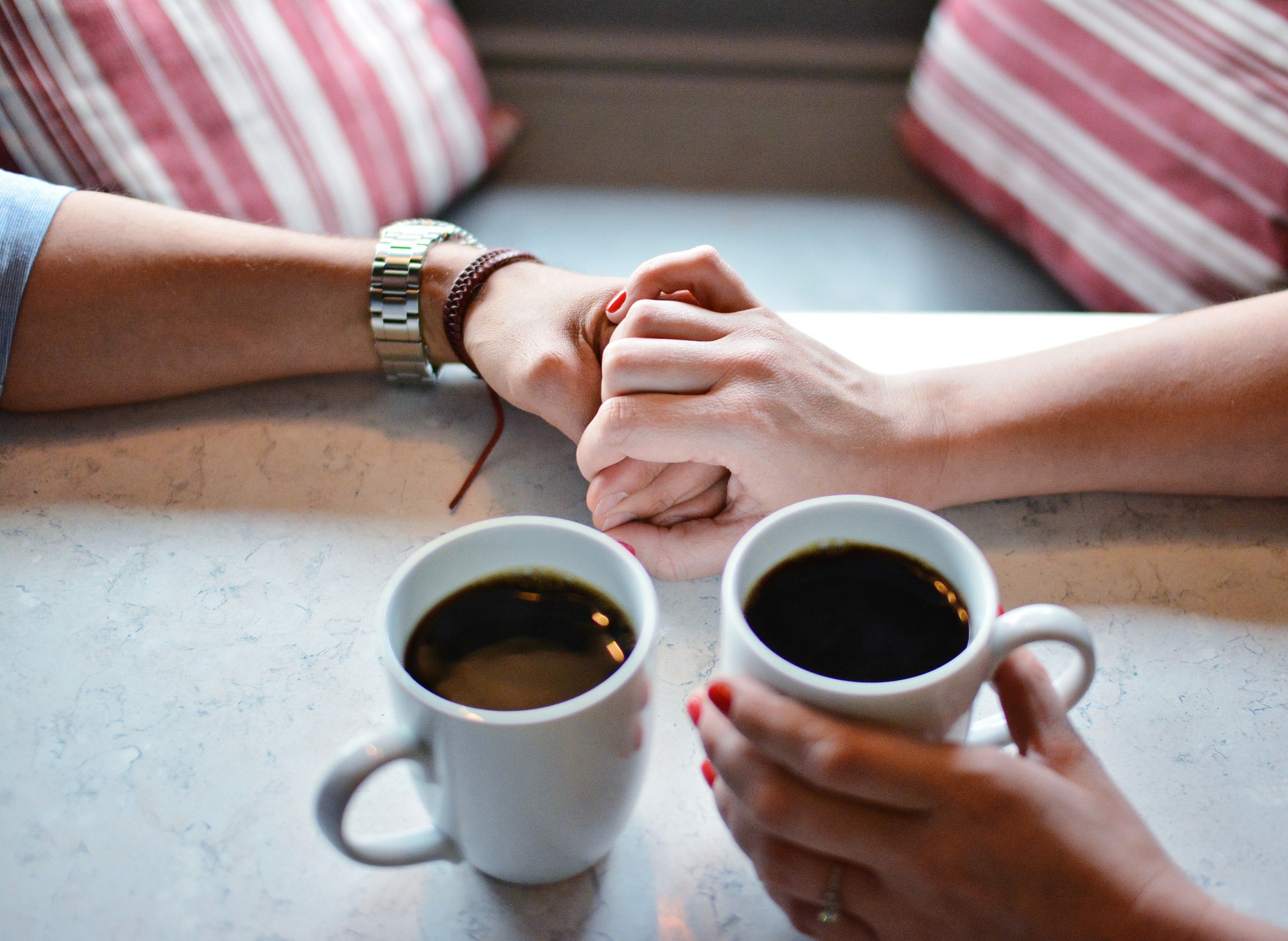 コーヒーとともに手を握る男女